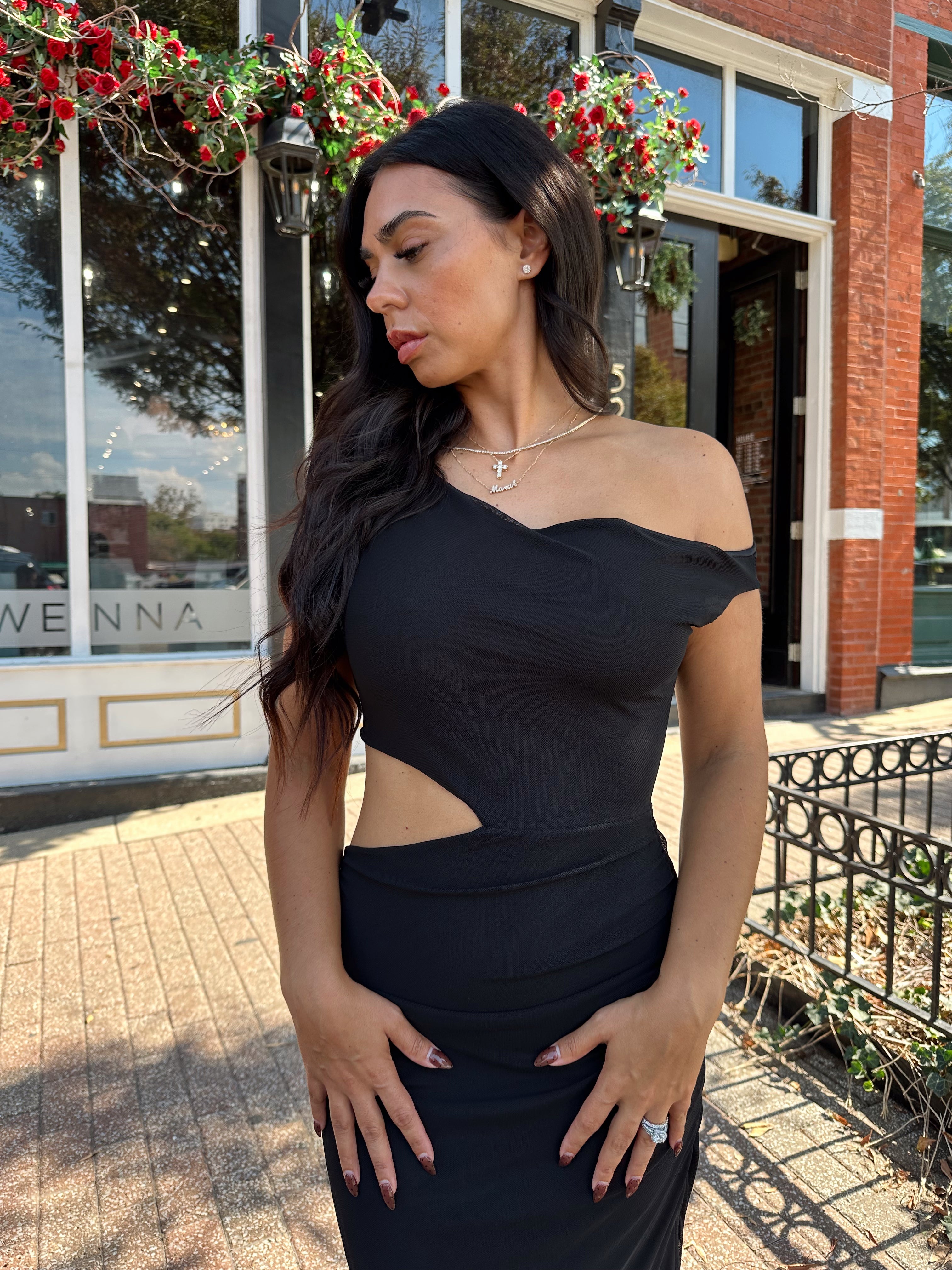 Woman wearing black mesh maxi dress with side cutout, and off the shoulder asymmetrical neckline.