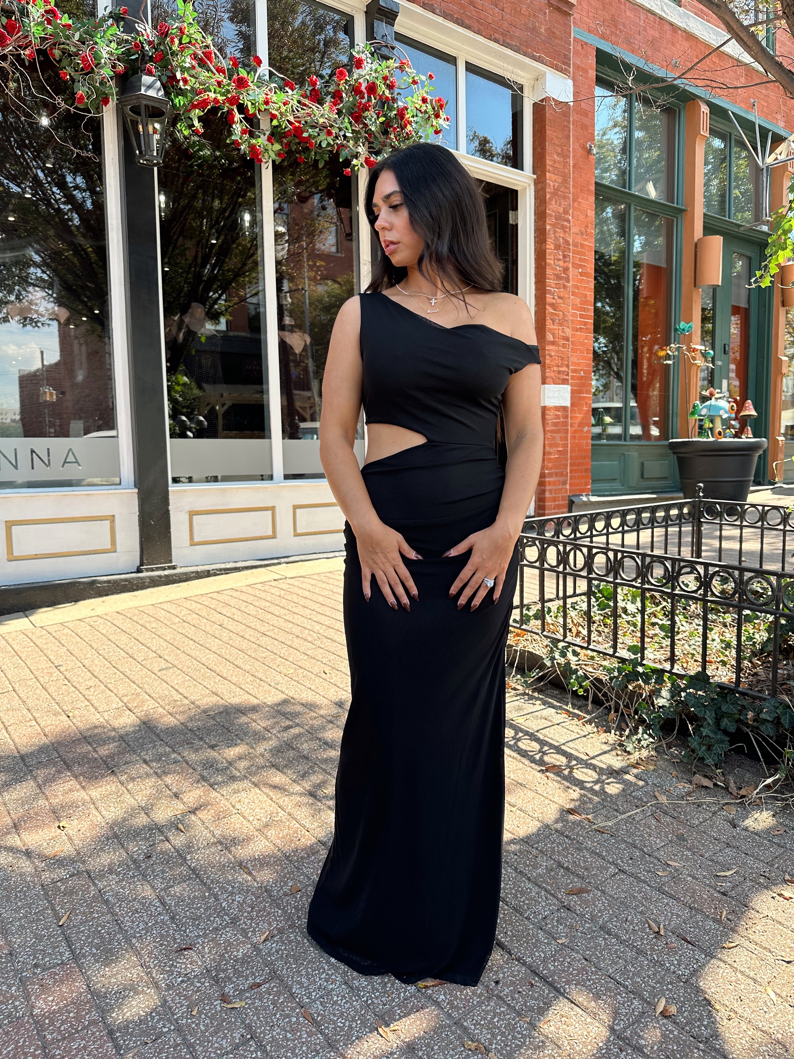 Woman wearing black mesh maxi dress with side cutout, and off the shoulder asymmetrical neckline.