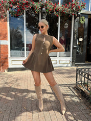 Woman wearing brown fit to flare mini dress with keyhole cutout and gold buttons.