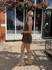 Woman wearing brown fit to flare mini dress with keyhole cutout and gold buttons.