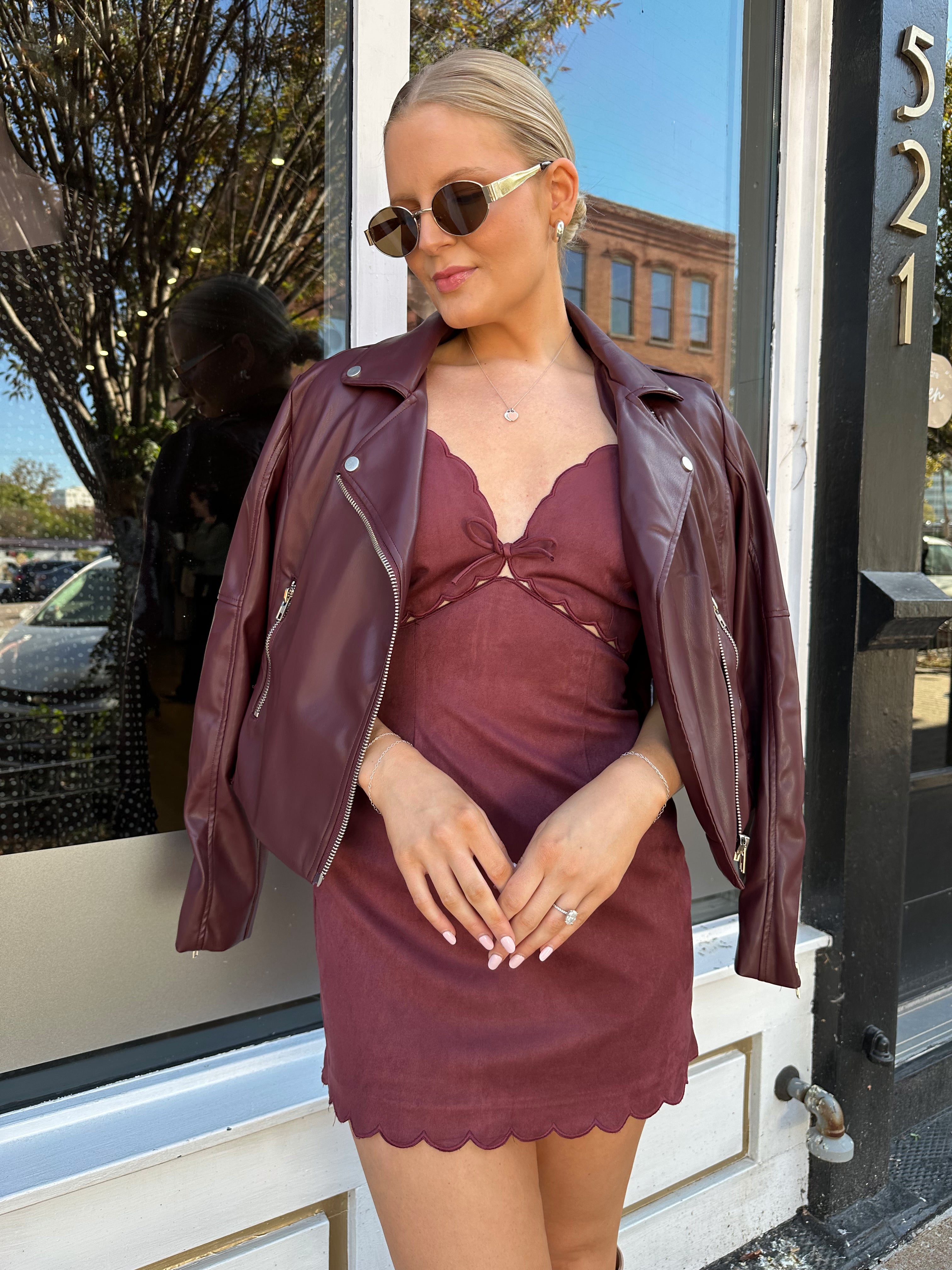 Woman wearing burgundy suede mini dress with scallop detail.