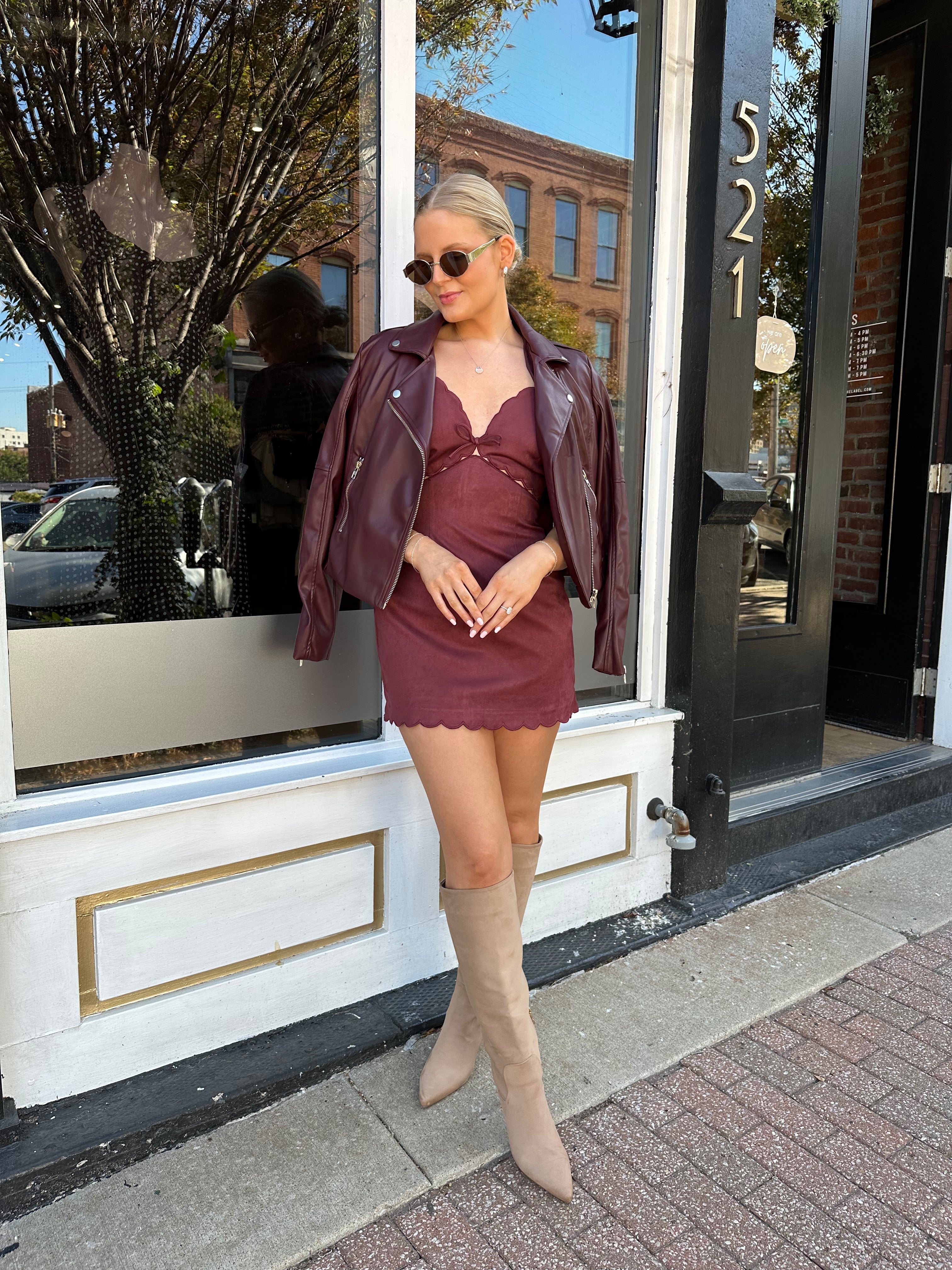 Woman wearing burgundy suede mini dress with scallop detail.