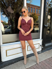 Woman wearing burgundy suede mini dress with scallop detail.