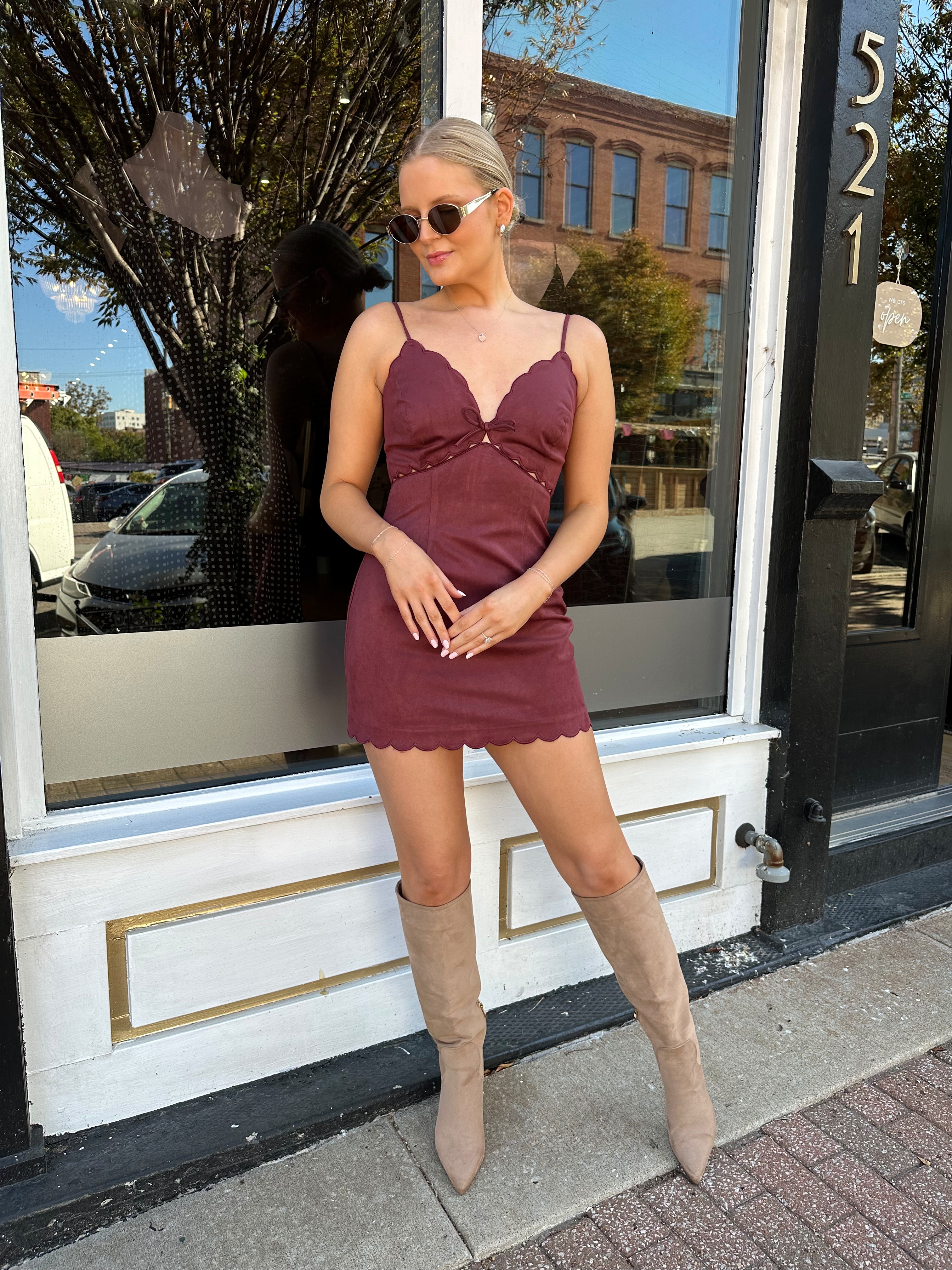 Woman wearing burgundy suede mini dress with scallop detail.