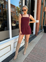 Woman wearing rose tailored mini dress with square neckline and front pockets.