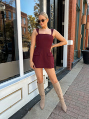 Woman wearing rose tailored mini dress with square neckline and front pockets.