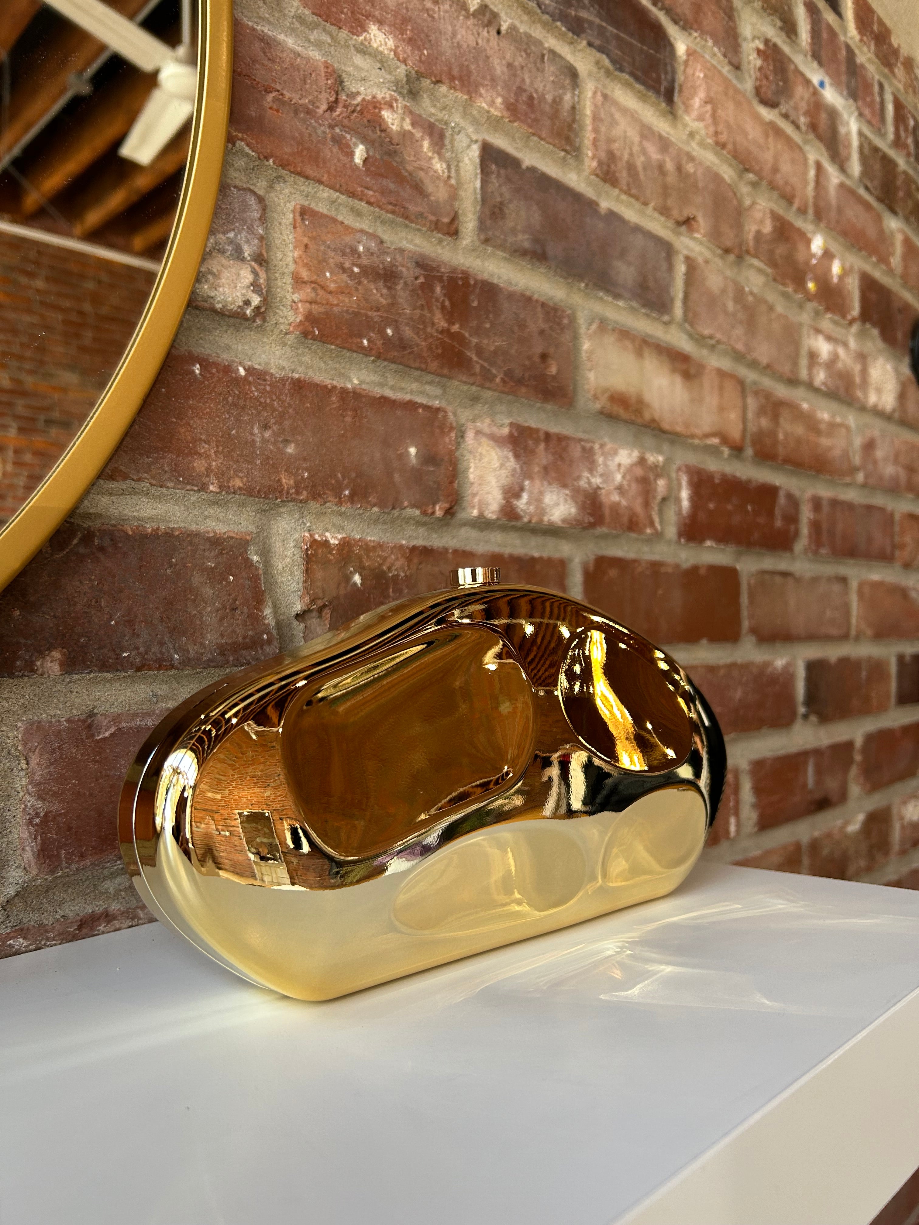 Gold hardshell clutch bag with detachable chain.