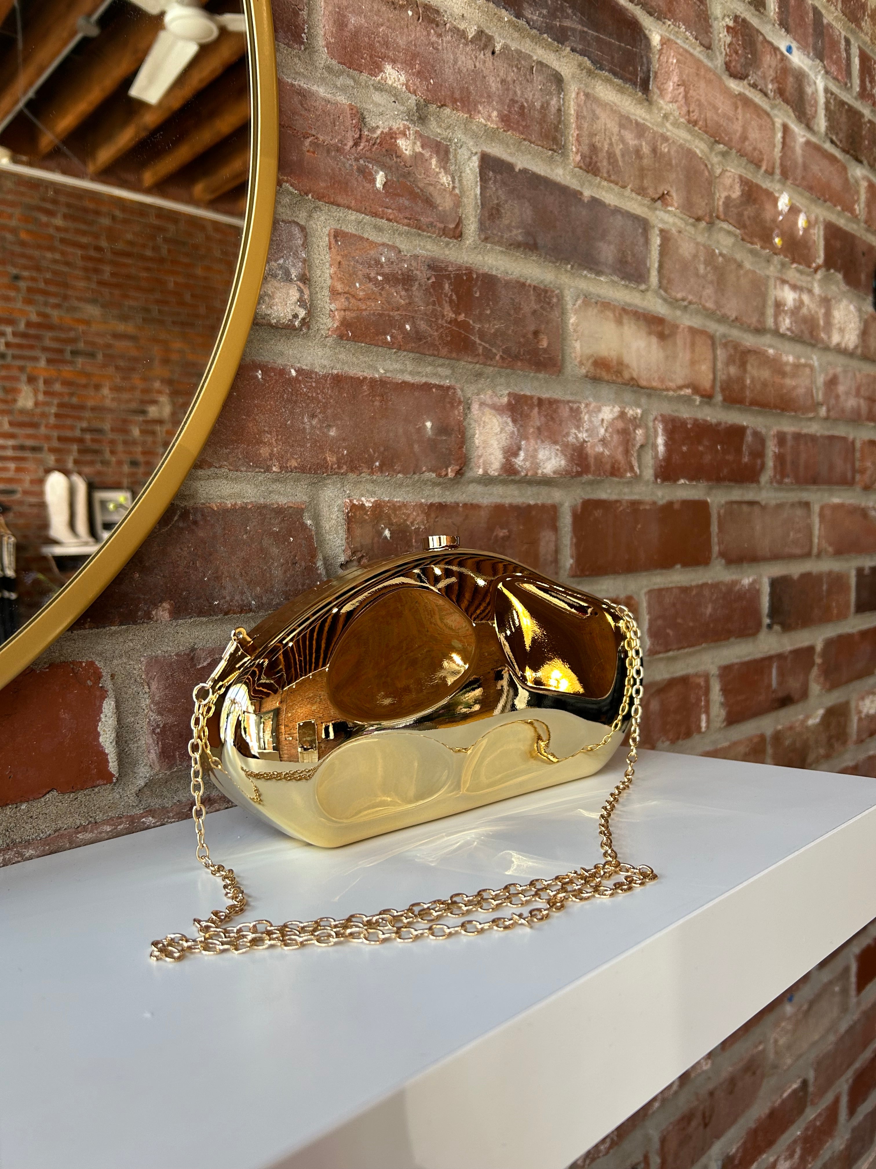 Gold hardshell clutch bag with detachable chain.