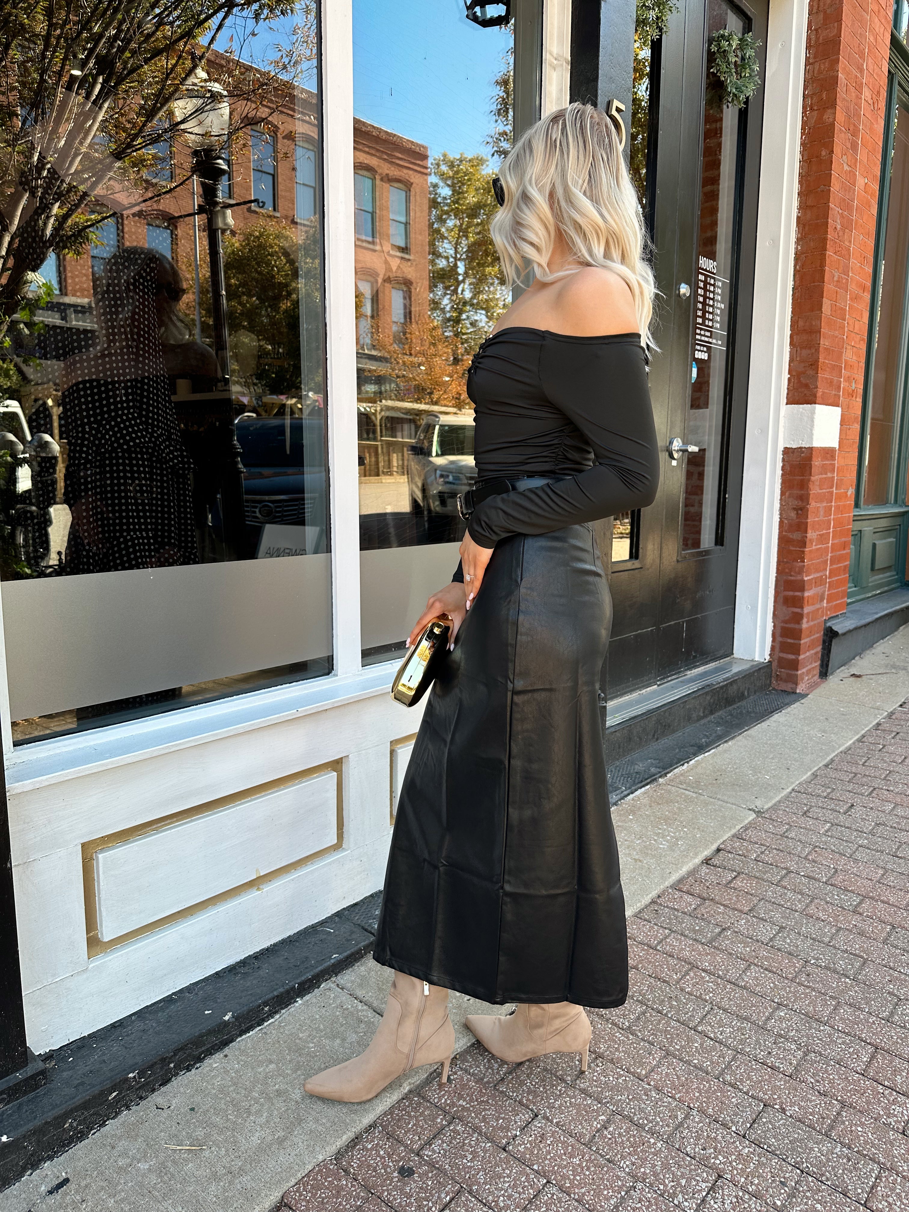 Woman wearing black leather midi skirt with slit up the back.