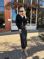 Woman wearing black leather midi skirt with slit up the back.