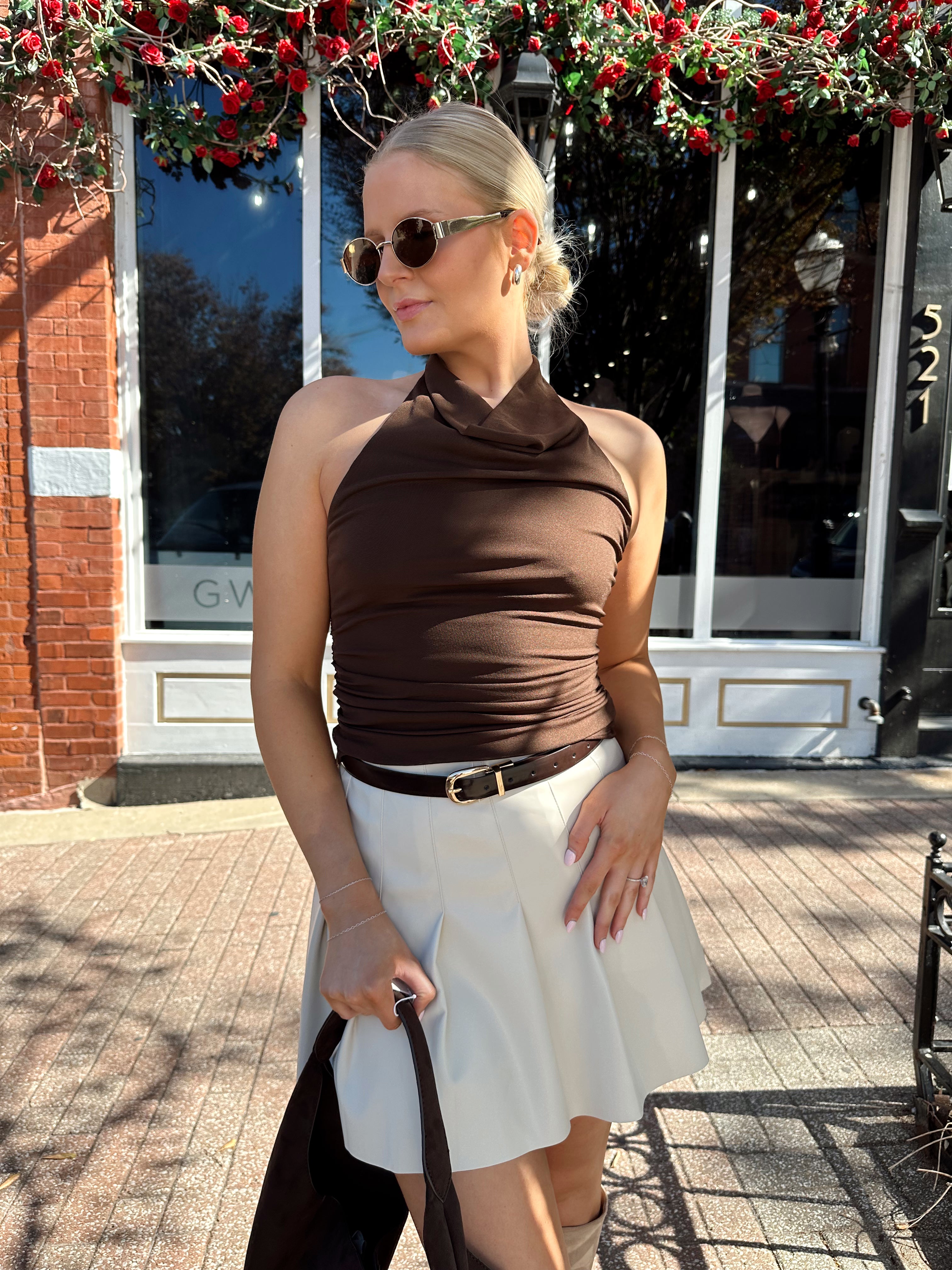 Woman wearing brown mesh, cowl, halter neck top.