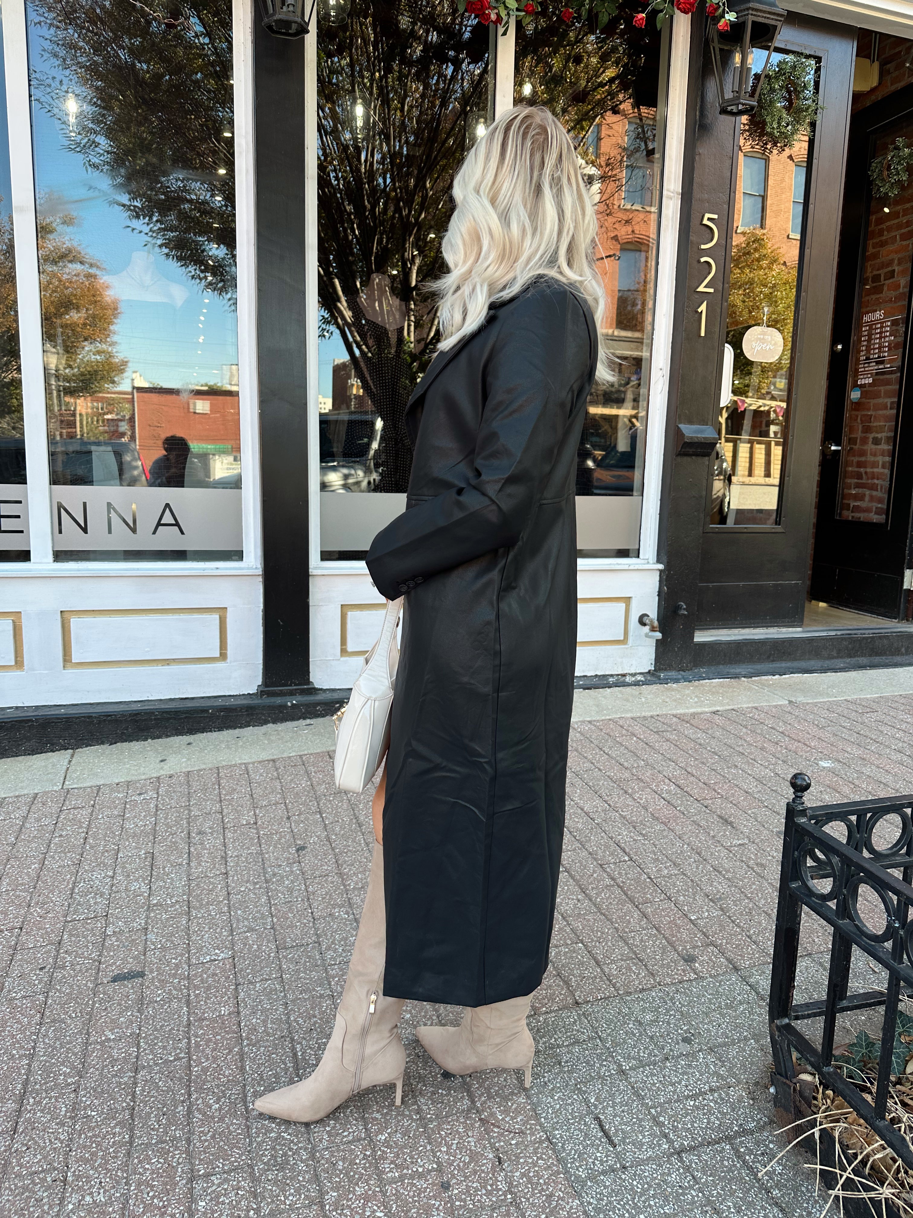 Woman wearing black tailored trench coat and knit sweater mini dress.