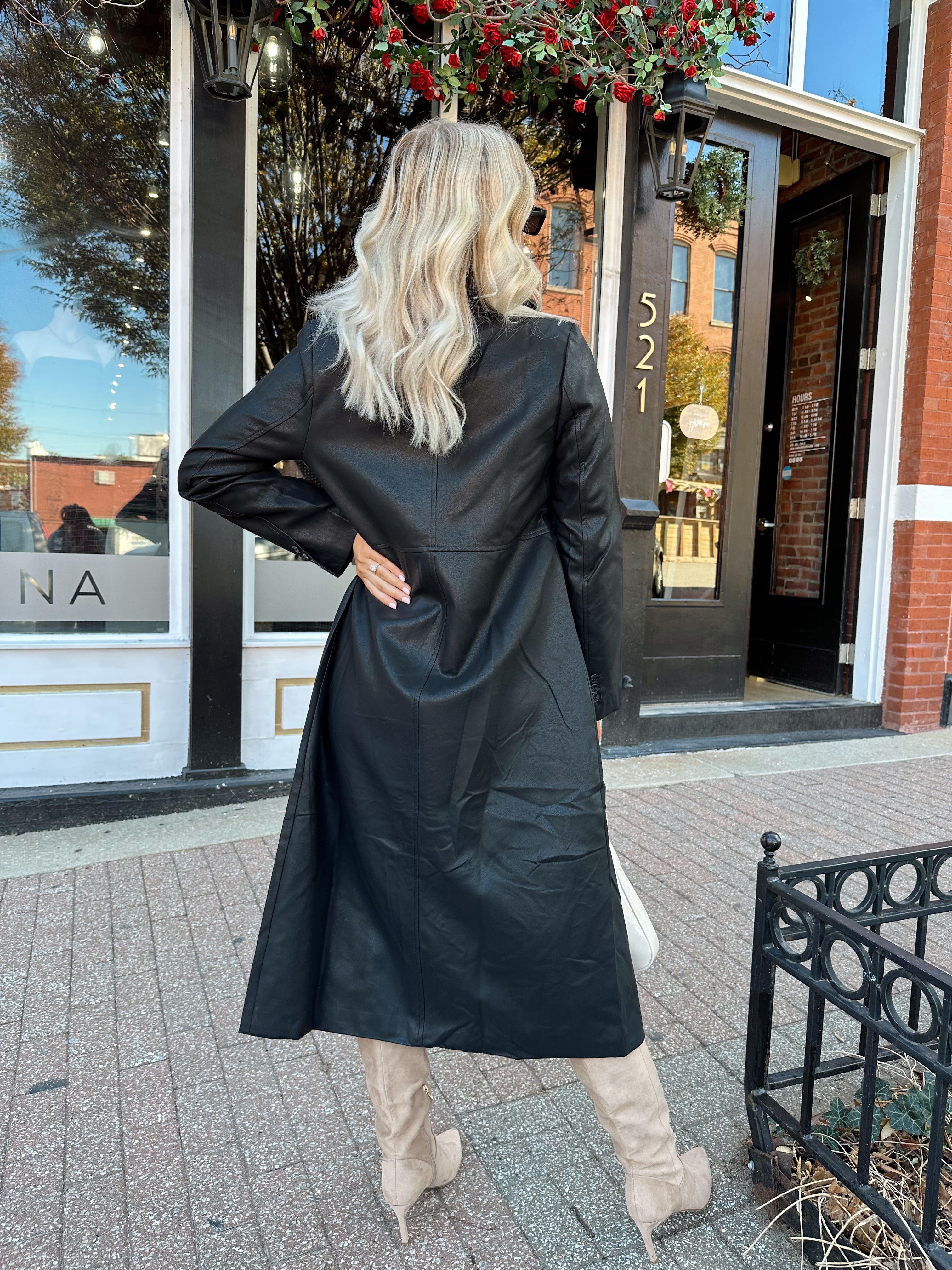 Woman wearing black tailored trench coat and knit sweater mini dress.