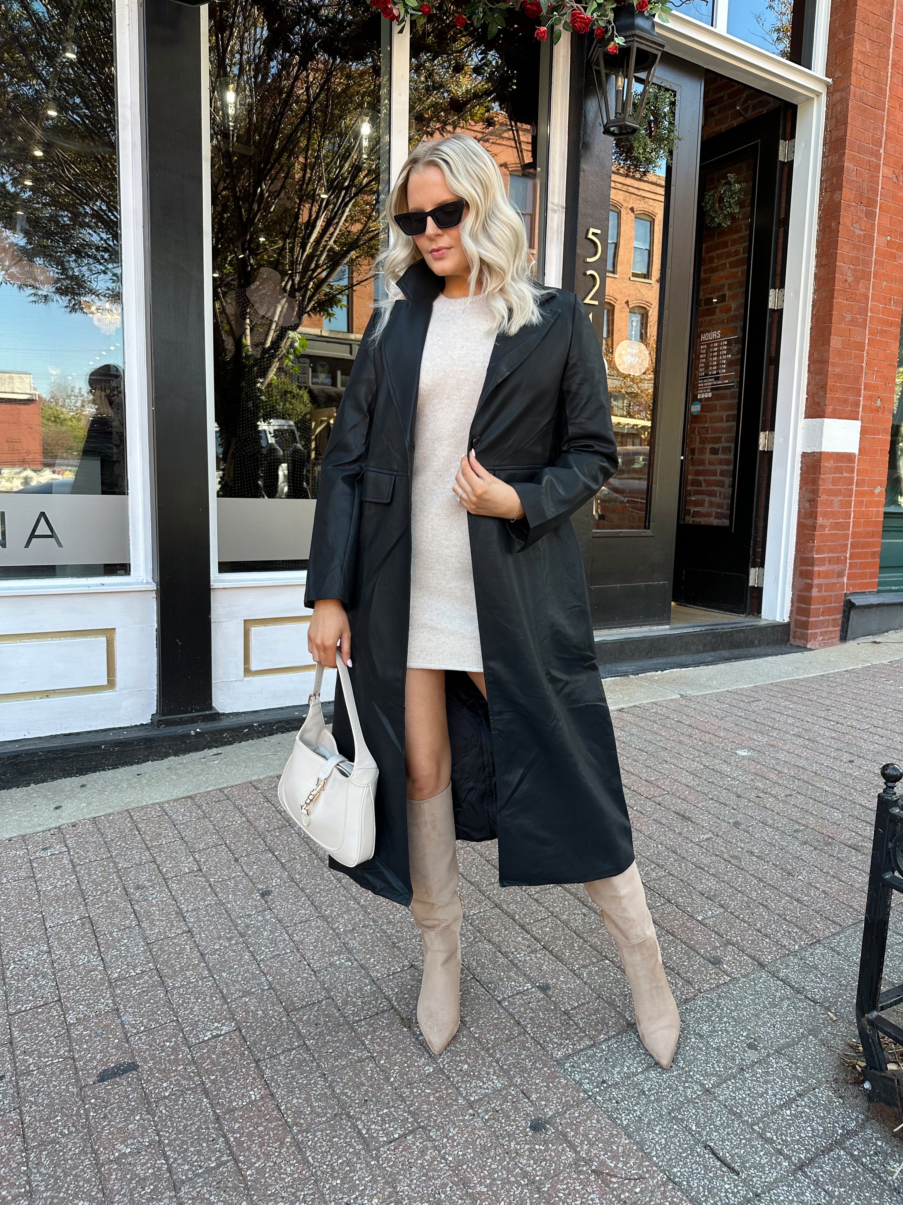 Woman wearing black tailored trench coat and knit sweater mini dress.