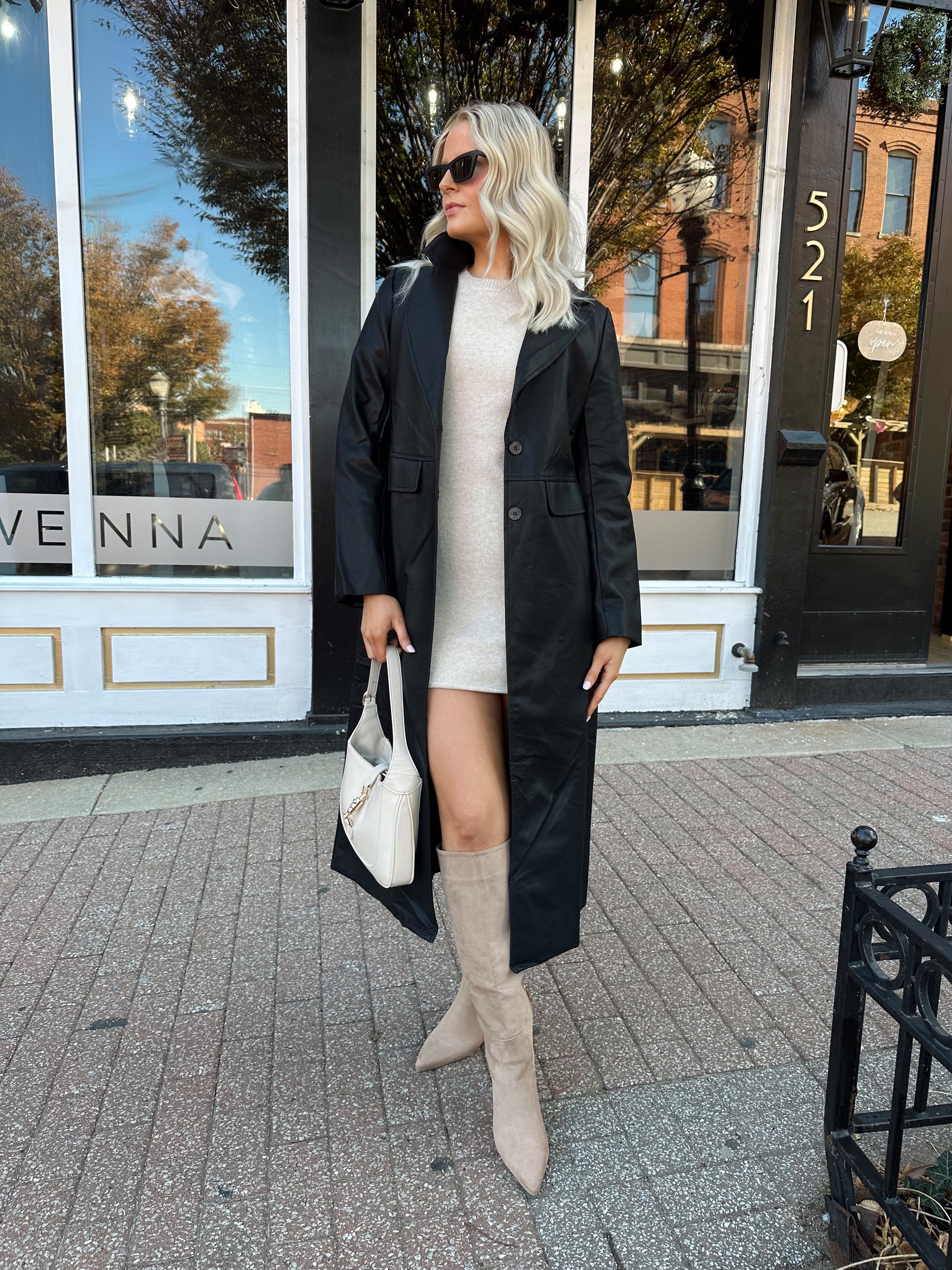 Woman wearing black tailored trench coat and knit sweater mini dress.