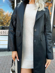 Woman wearing black tailored trench coat and knit sweater mini dress.