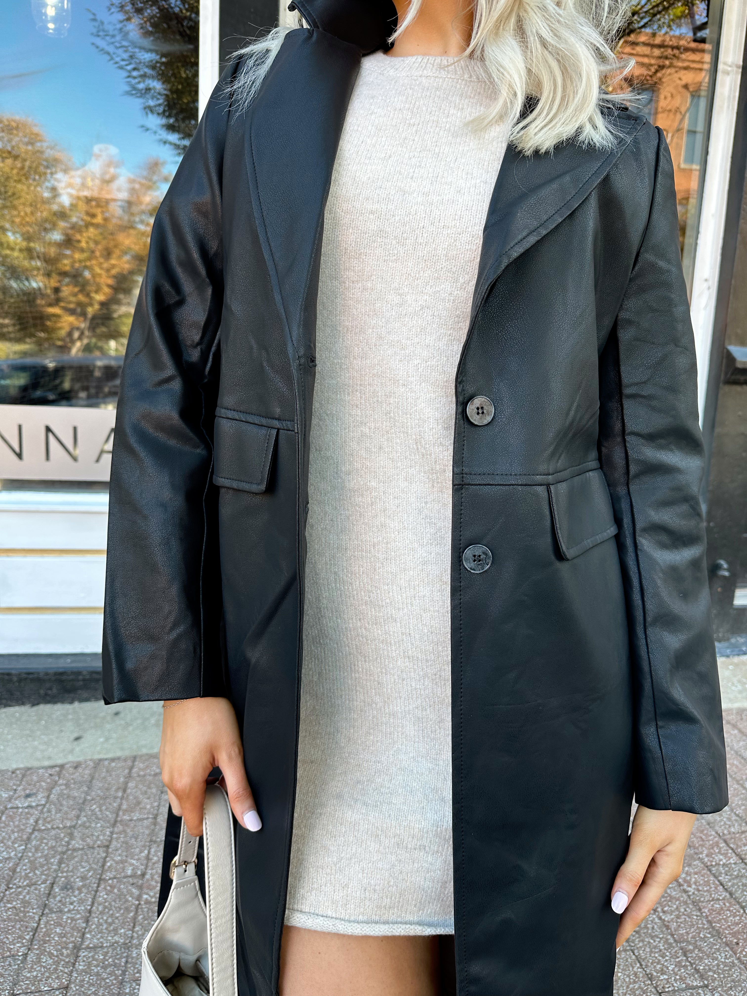 Woman wearing black tailored trench coat and knit sweater mini dress.