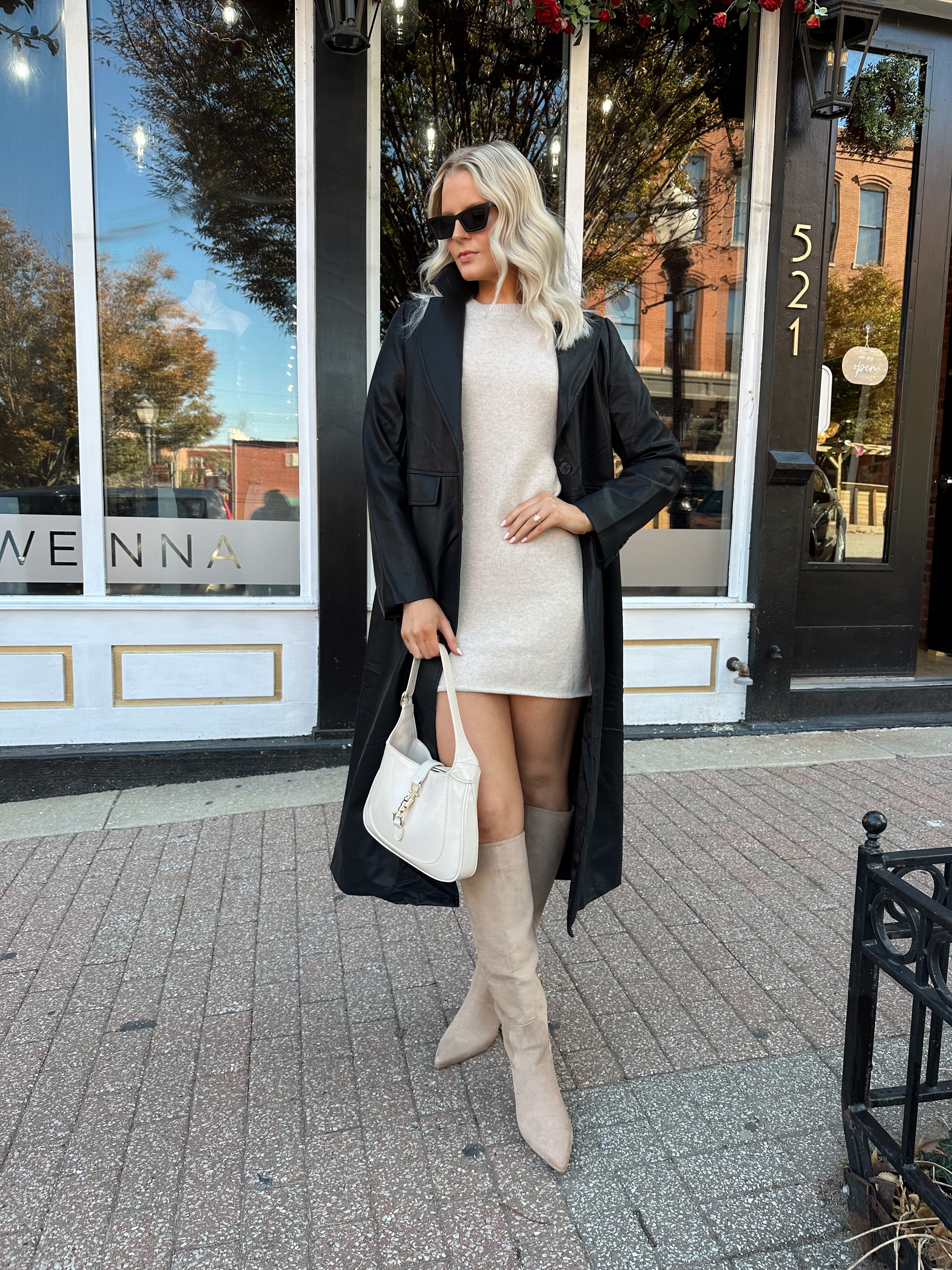 Woman wearing black tailored trench coat and knit sweater mini dress.