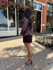 Woman wearing burgundy matte leather jacket with burgundy mini skort.