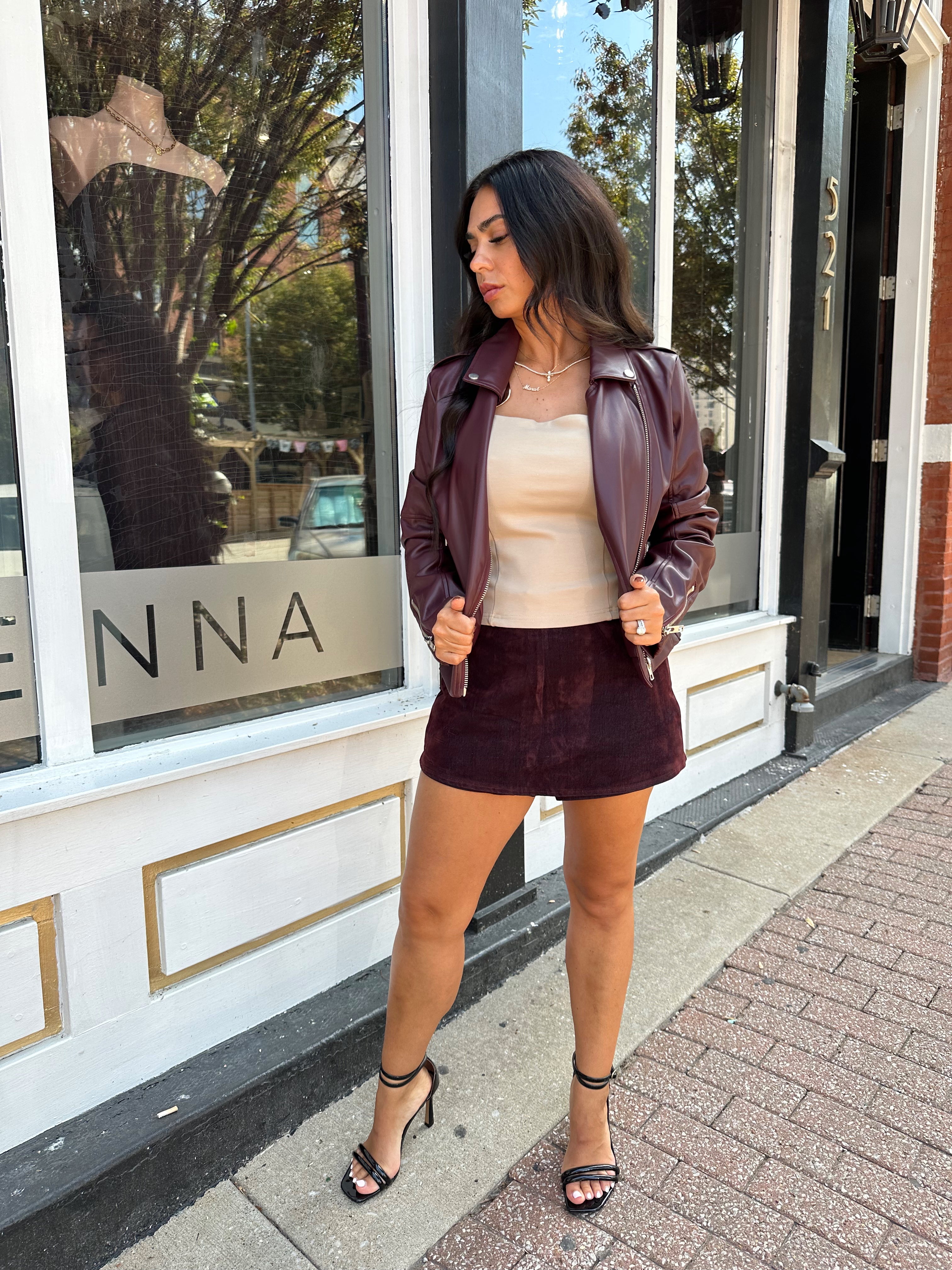 Woman wearing burgundy matte leather jacket with burgundy mini skort.