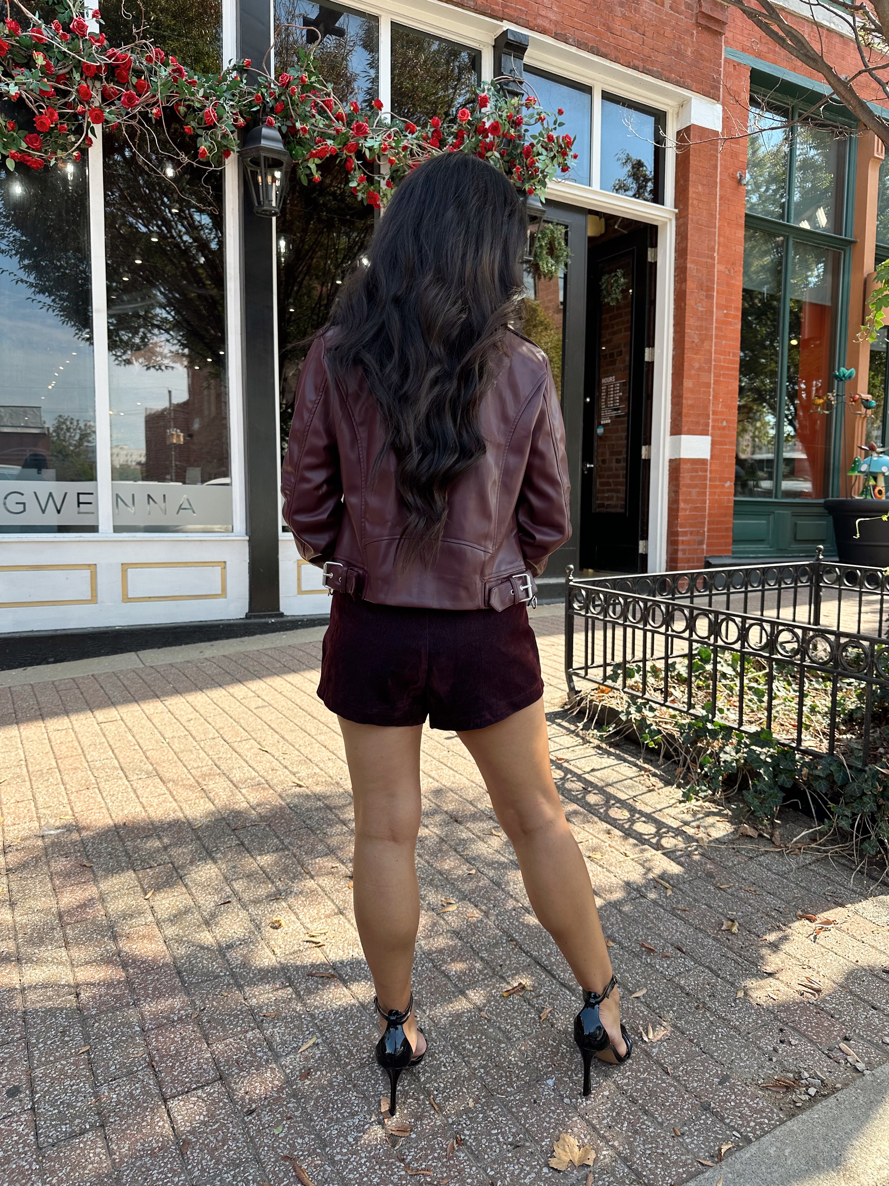 Woman wearing burgundy matte leather jacket with burgundy mini skort.
