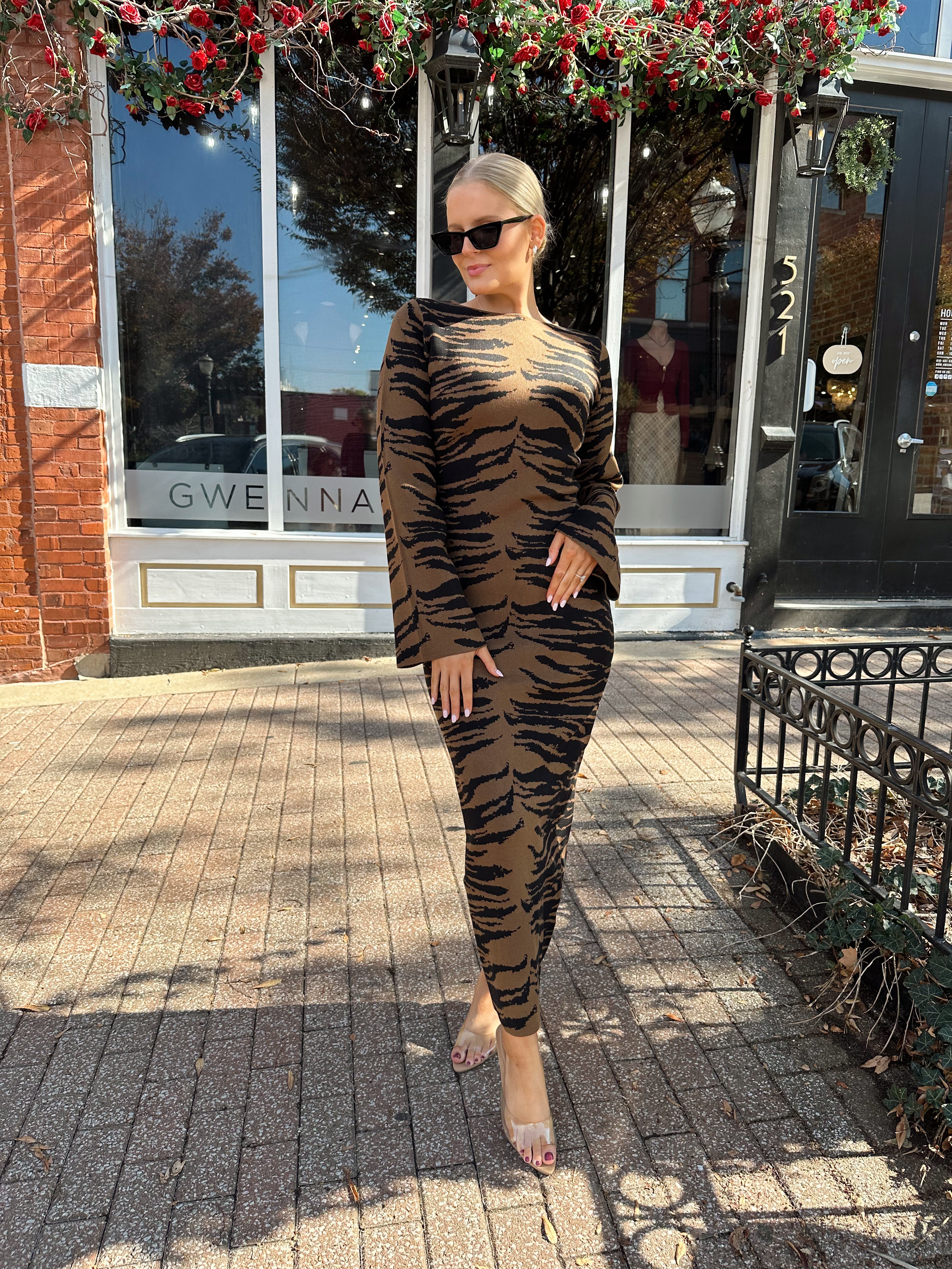 Woman wearing brown zebra print long sleeve sweater dress.