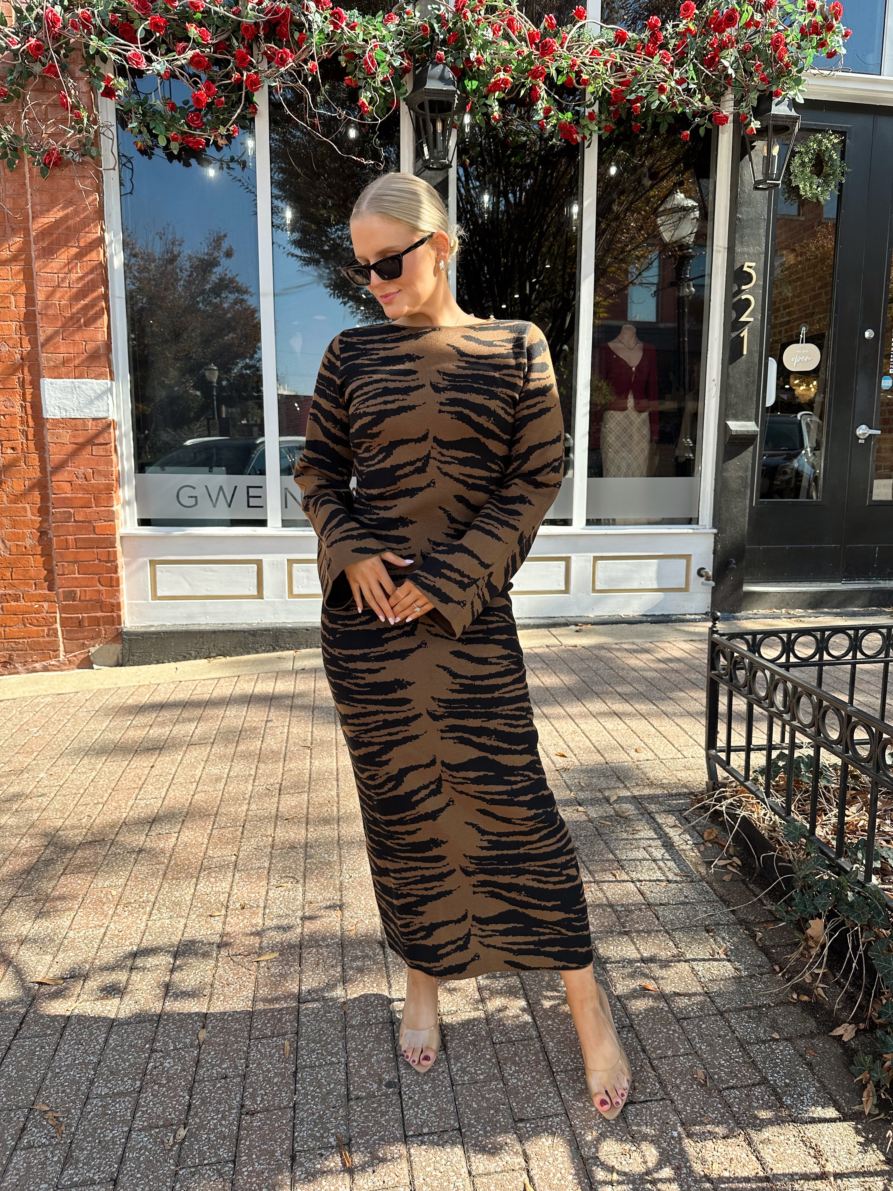 Woman wearing brown zebra print long sleeve sweater dress.