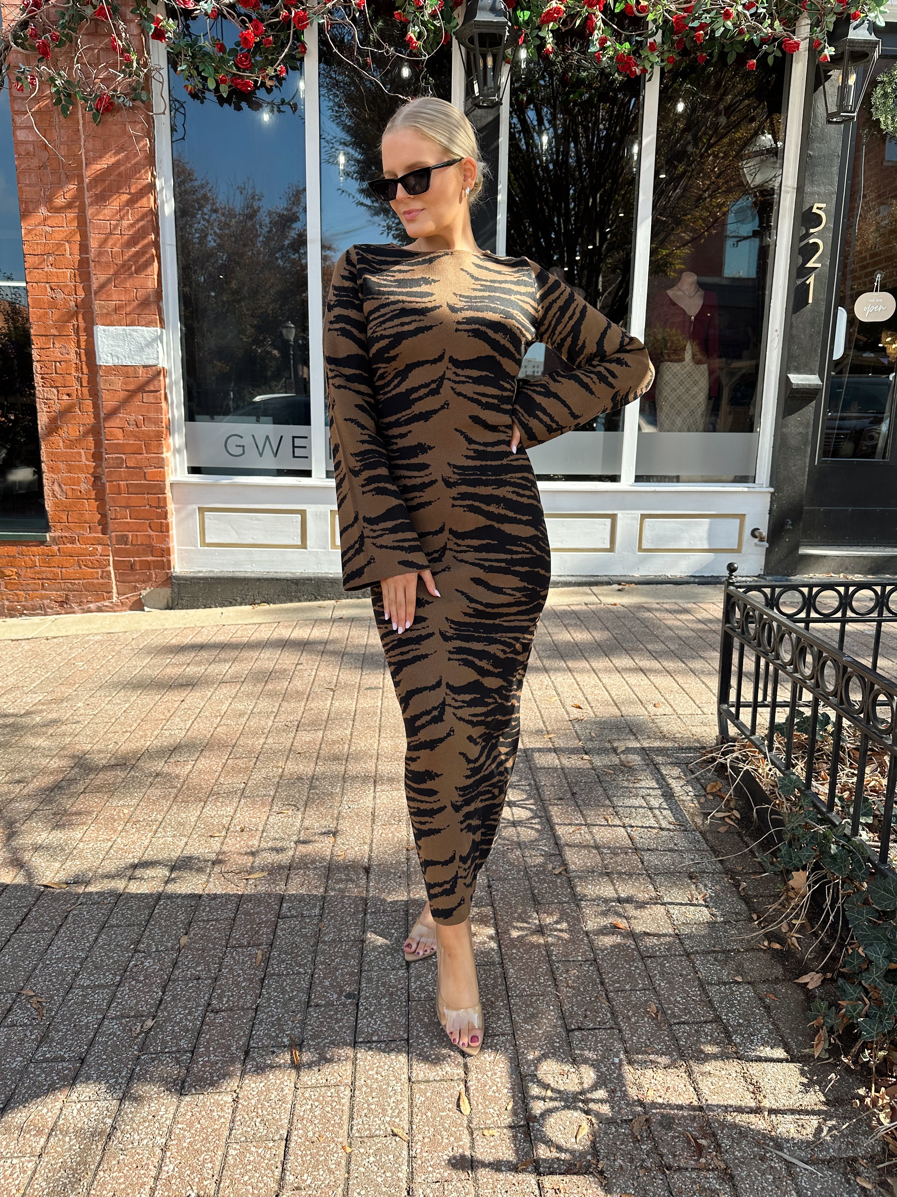 Woman wearing brown zebra print long sleeve sweater dress.