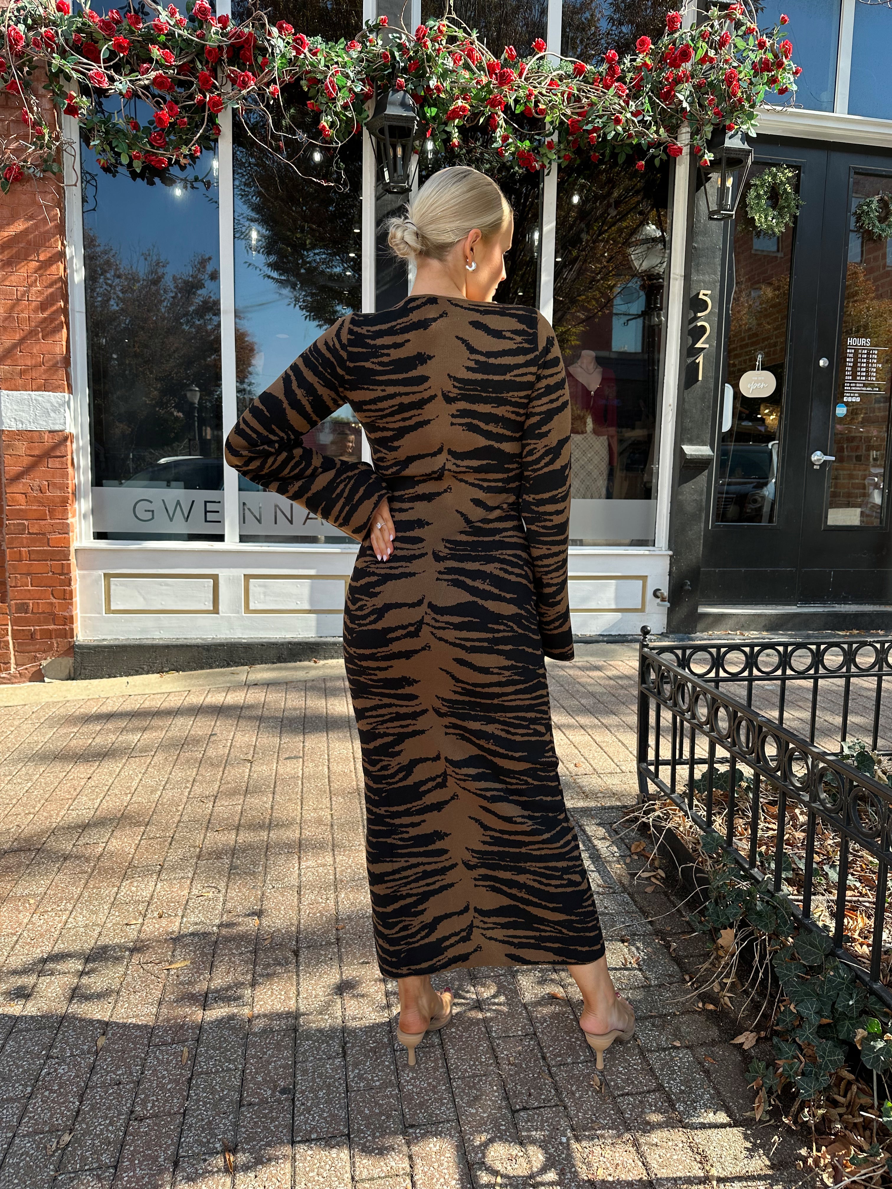 Woman wearing brown zebra print long sleeve sweater dress.
