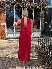 Woman wearing strapless red plissé maxi dress with lace up back, and detachable scarf.