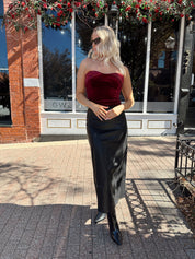 Woman wearing burgundy velvet strapless top with satin neckline.