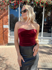 Woman wearing burgundy velvet strapless top with satin neckline.