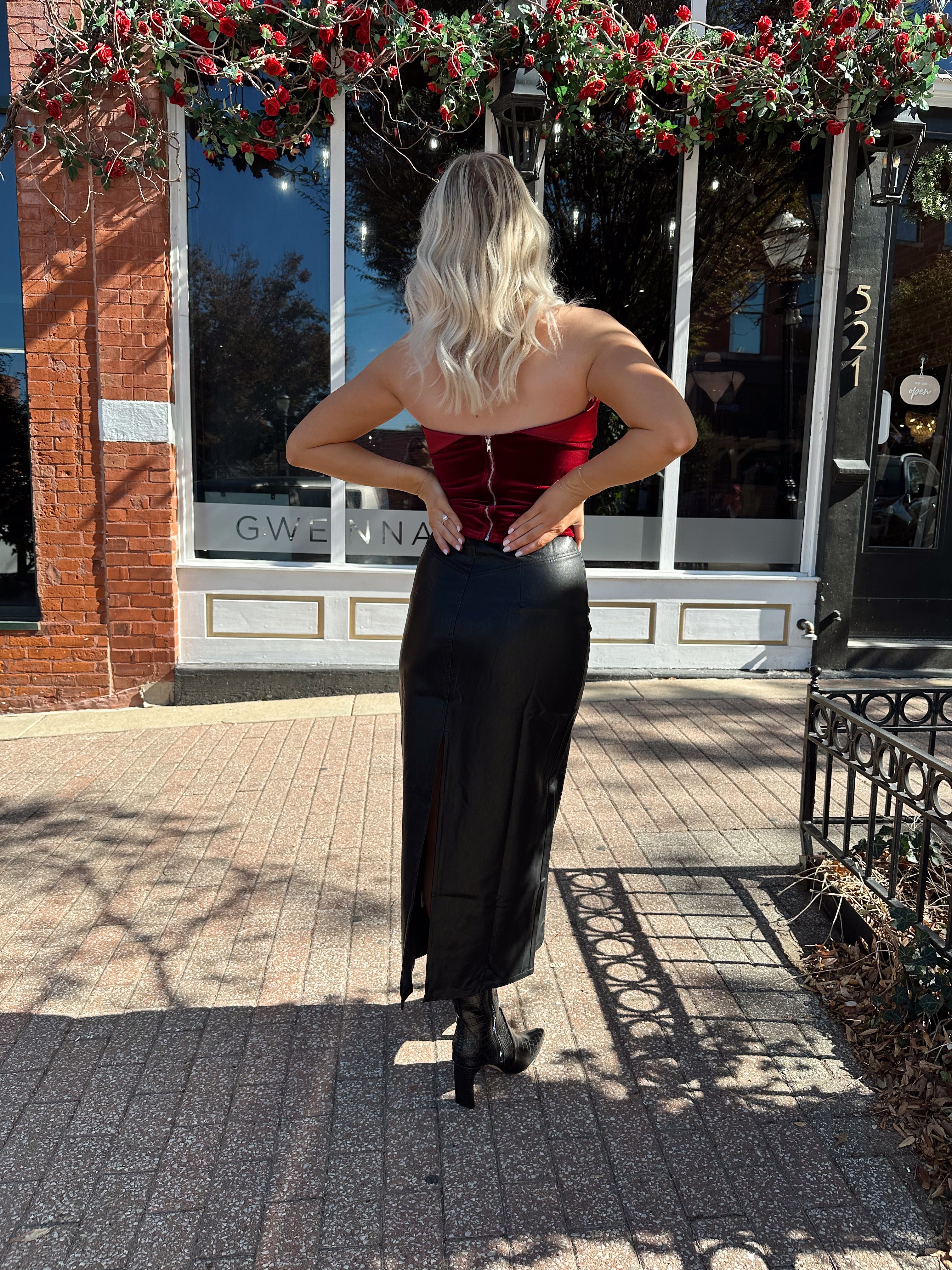 Woman wearing burgundy velvet strapless top with satin neckline.