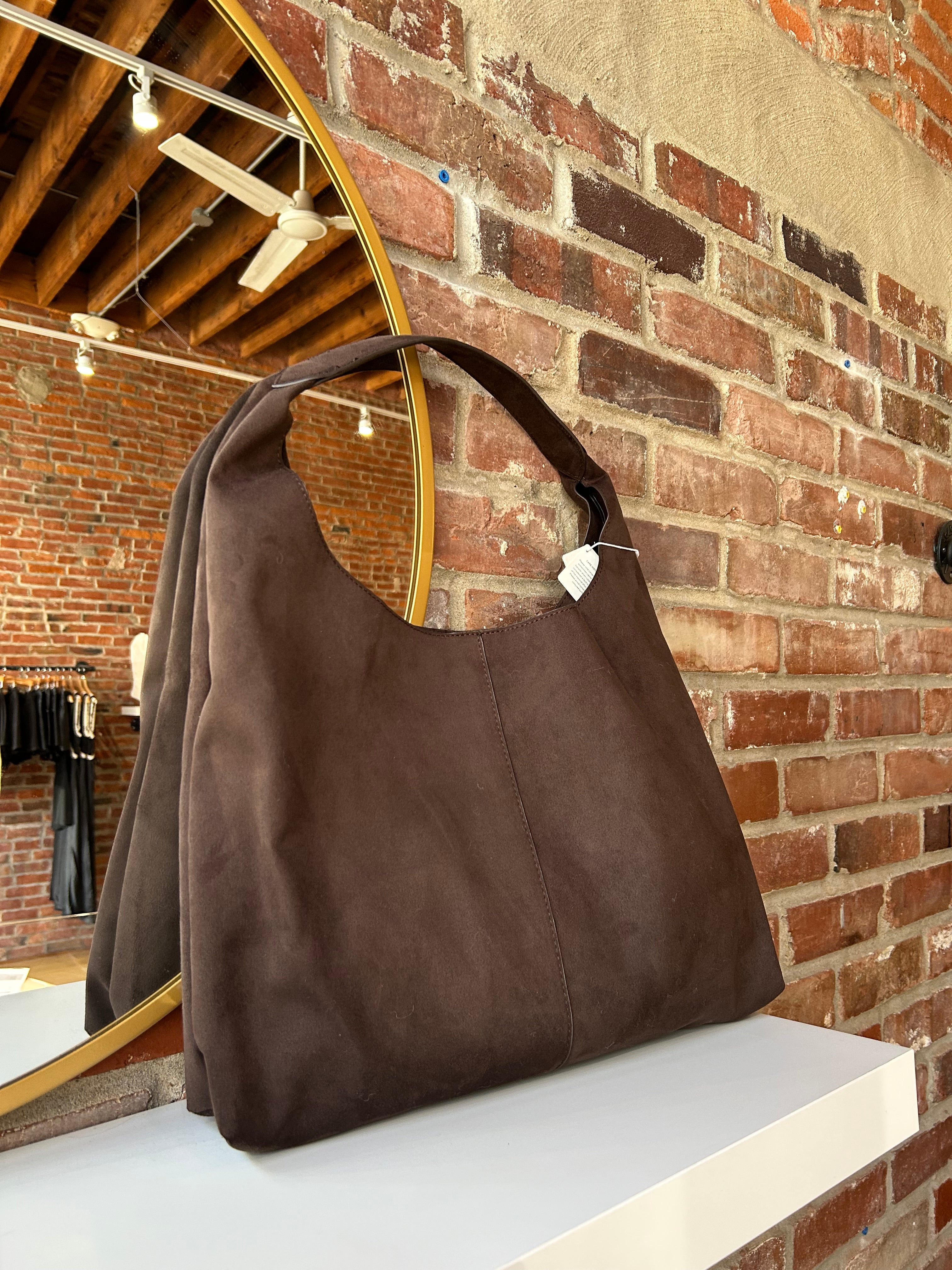 Dark brown suede shoulder bag with magnetic closure.