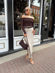 Woman wearing tan satin maxi skirt with elastic waist band and brown off the shoulder bodysuit.