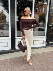 Woman wearing tan satin maxi skirt with elastic waist band and brown off the shoulder bodysuit.