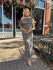 Woman wearing zebra print satin maxi dress with asymmetrical neckline.