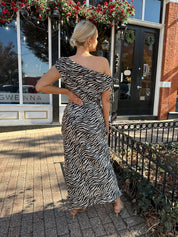 Woman wearing zebra print satin maxi dress with asymmetrical neckline.