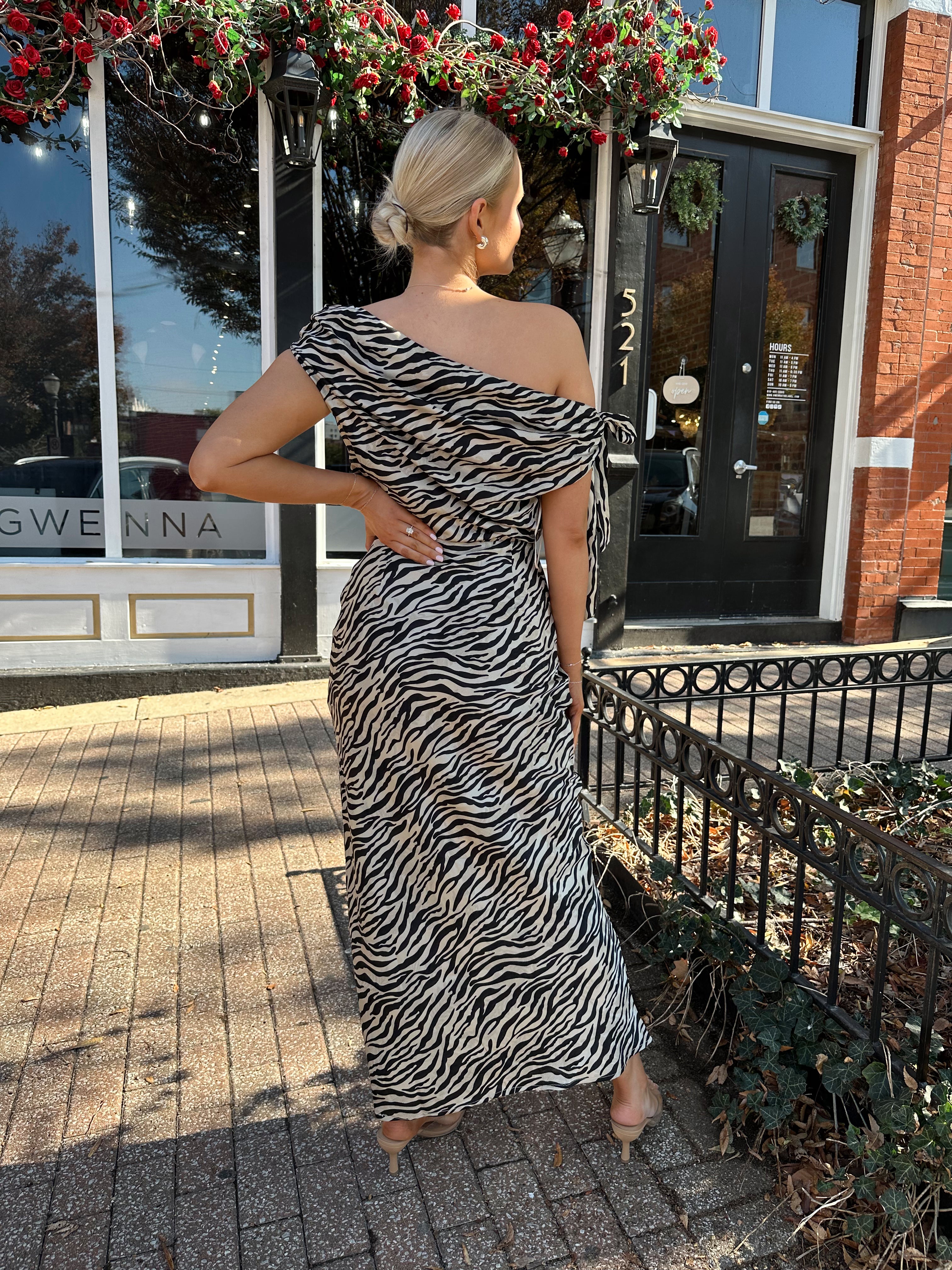 Woman wearing zebra print satin maxi dress with asymmetrical neckline.