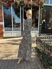 Woman wearing long sleeve zebra print maxi dress with wide sleeve.