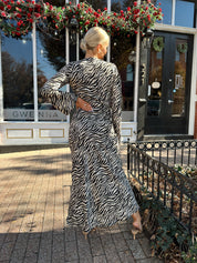 Woman wearing long sleeve zebra print maxi dress with wide sleeve.