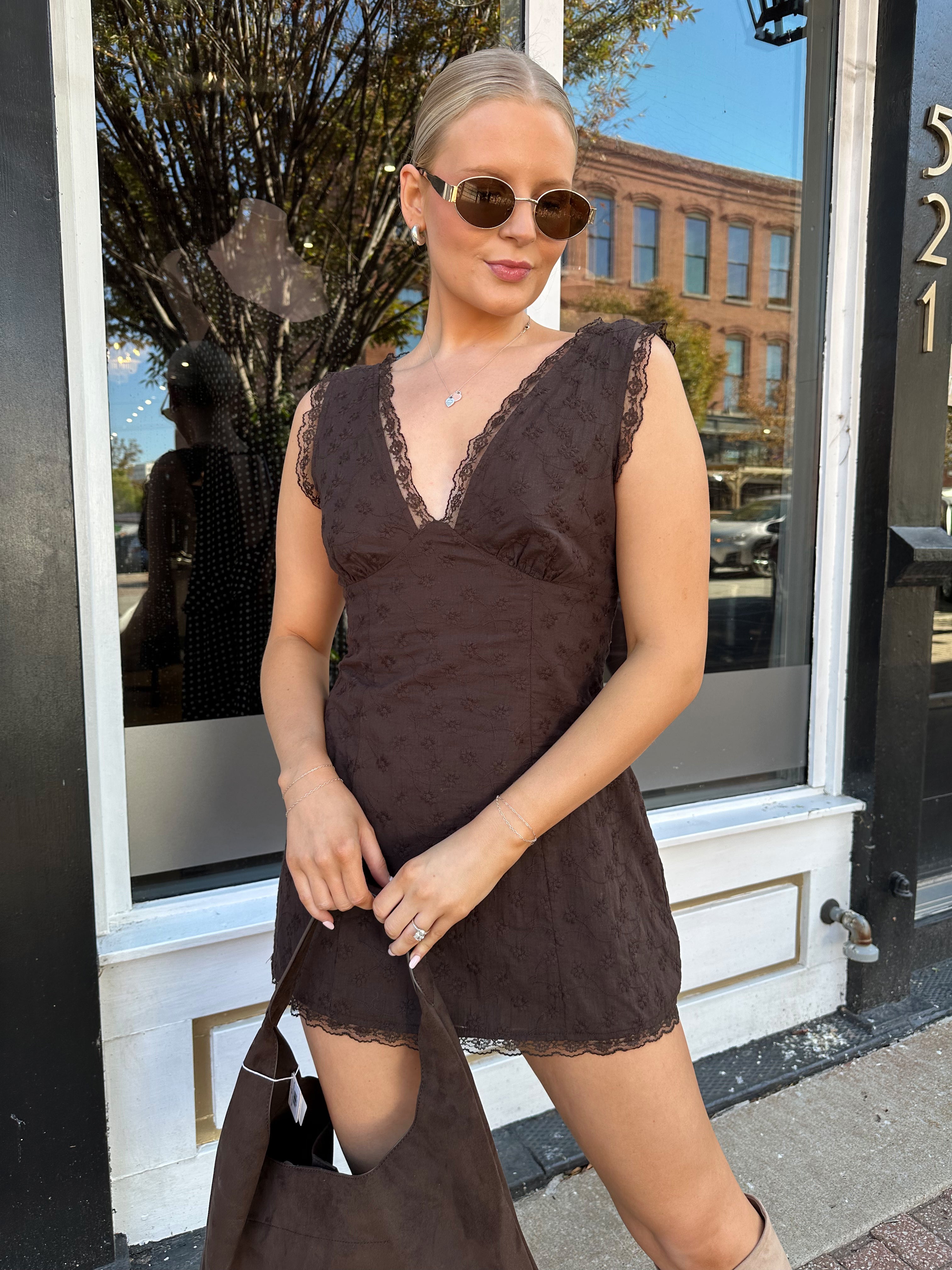 Model wearing brown eyelet lace mini dress with open back and scalloped trim.