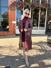 Woman wearing burgundy knit mock neck mini dress with leather trench coat.