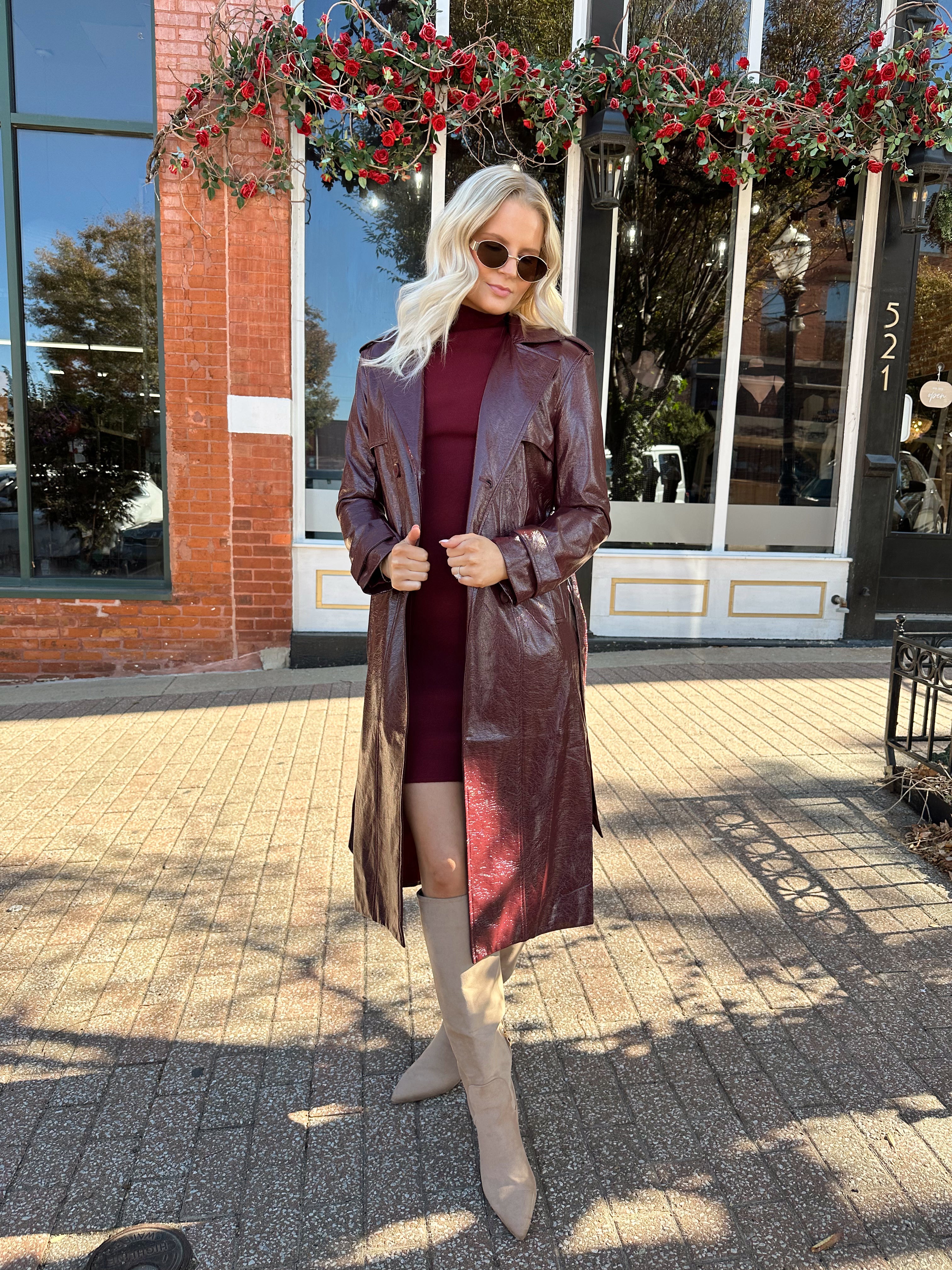 Woman wearing burgundy knit mock neck mini dress with leather trench coat.