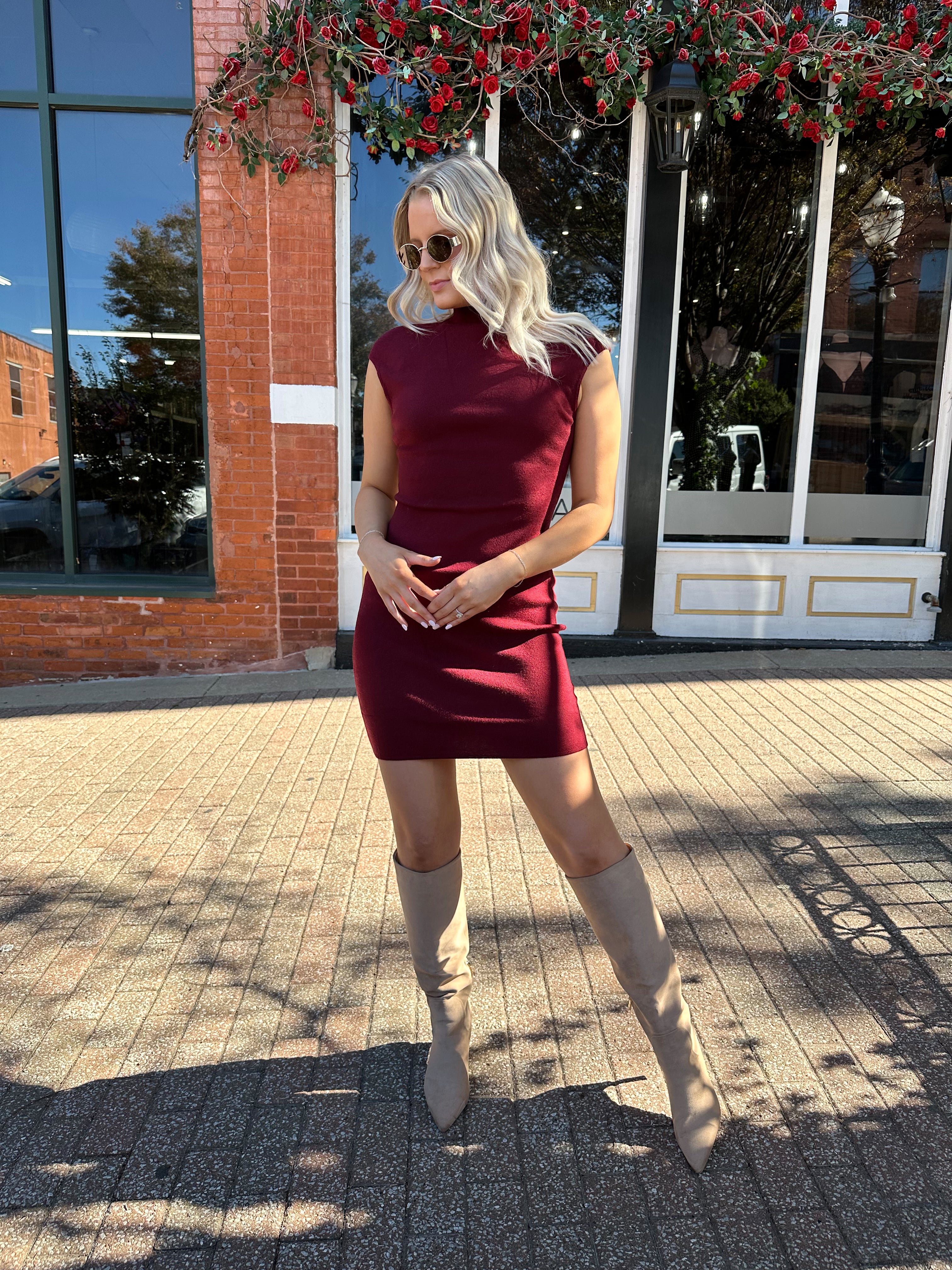 Woman wearing burgundy knit mock neck mini dress with leather trench coat.
