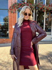 Woman wearing burgundy knit mock neck mini dress with leather trench coat.