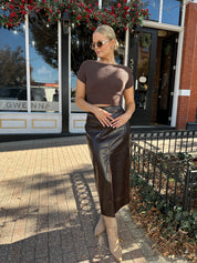 Woman wearing brown croc leather midi skirt with front slit.