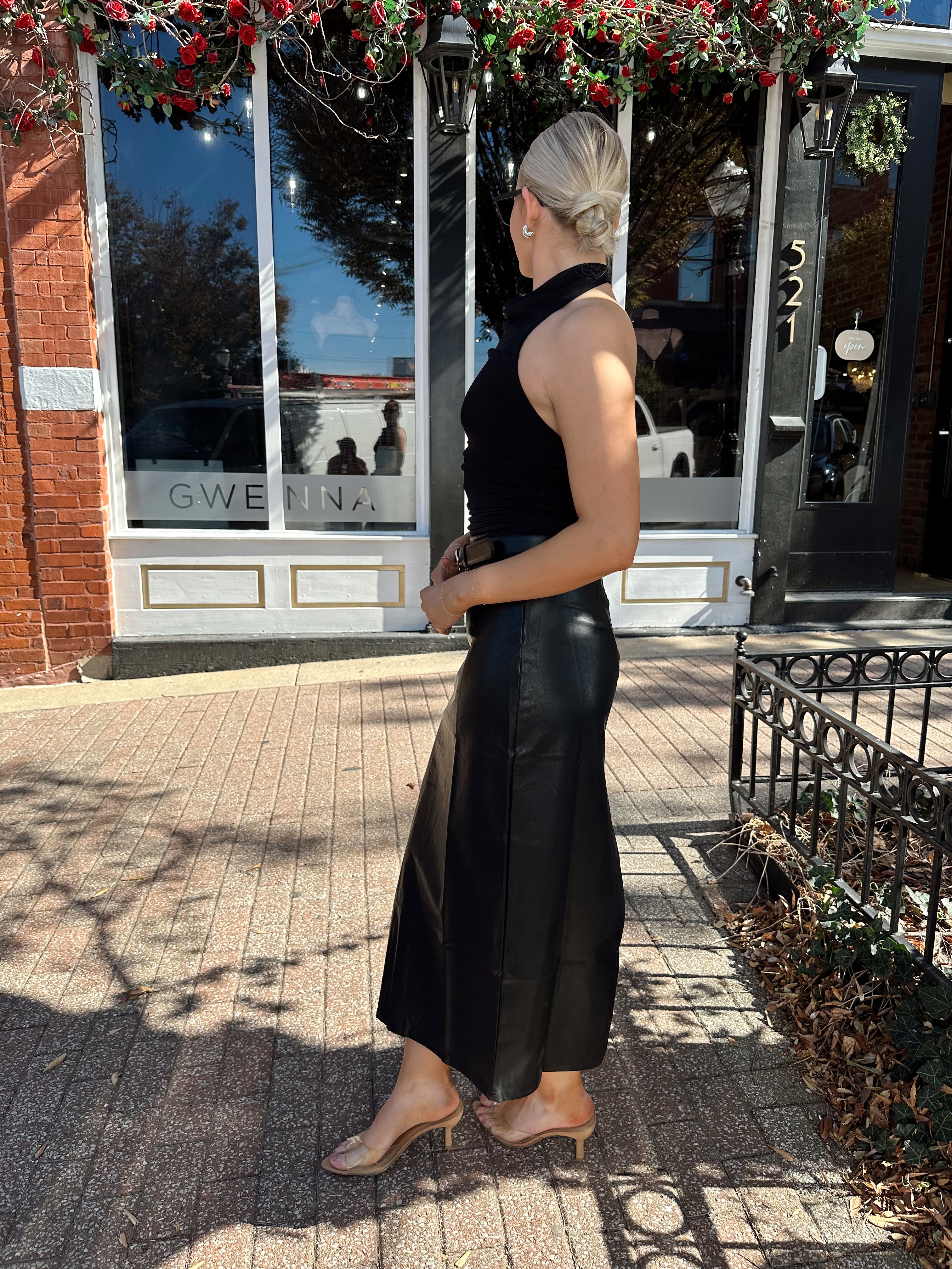 Woman wearing black mesh cowl, halter neck top.