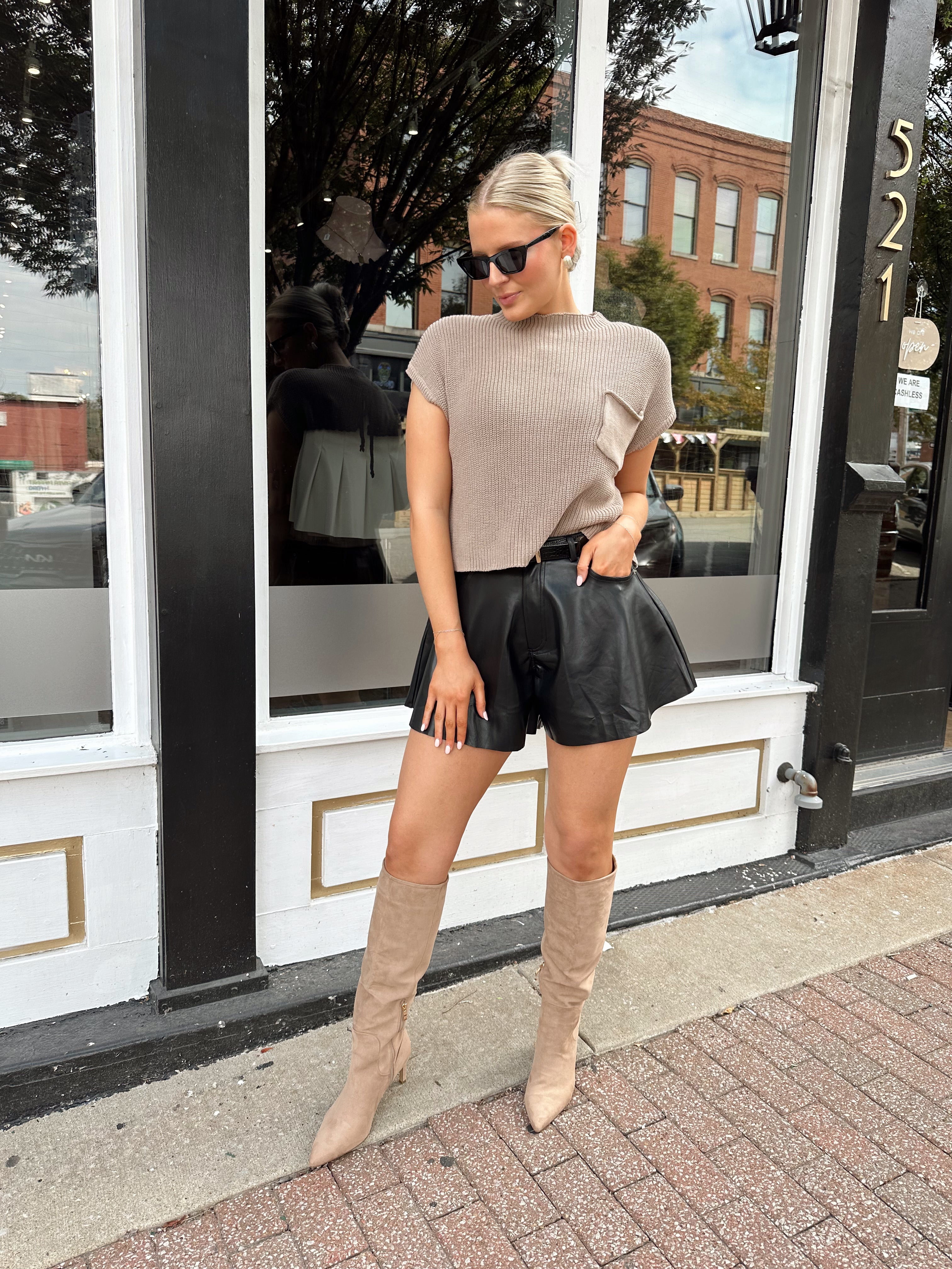 Black leather pleated short with oversized fit, skirt-like silhouette, and functional pockets