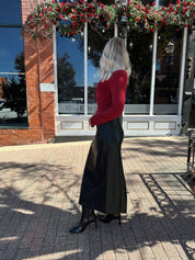 Woman wearing burgundy long sleeve top with twist front and gold detail.